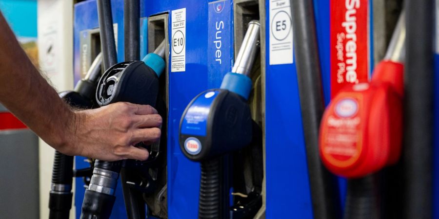 Ein Autofahrer hängt an einer Tankstelle in München eine Zapfpistole in die Zapfsäule.
