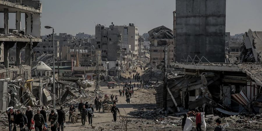 Palästinenser gehen nach dem Rückzug der israelischen Armee aus dem Norden des Gazastreifens neben beschädigten Gebäuden zurück in ihre Häuser. Foto: Omar Ishaq/dpa