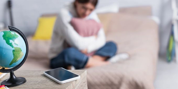 Rückzug und depressive Symptomatiken deuten manchmal auf Cybermobbing hin. Mädchen Traurig Bett Smartphone