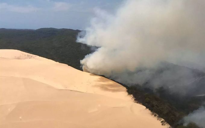 Rauch steigt auf aus einem Waldgebiet auf Fraser Island. Aufgrund von massiver Buschfeuer sollen Besucher der Insel fernbleiben. fraser island feuer brand