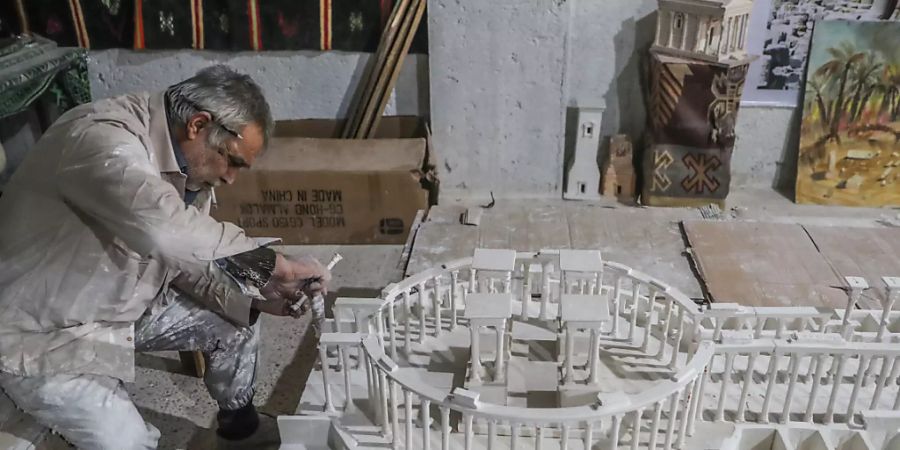 Ali Alsaleh in seiner Werkstatt bei der Arbeit an seinem Modell der antiken Oasenstadt Palmyra. Foto: Anas Alkharboutli/dpa