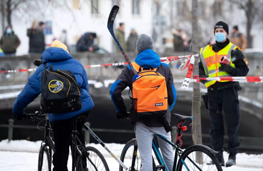 Polizisten weisen zwei Personen vom Nymphenburger Kanal weg.
