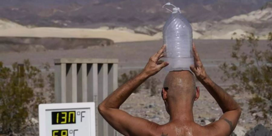 Ganz schön heiss: Ein Mann kühlt sich im «Death Valley»-Nationalpark im US-Bundesstaat Arizona bei 59 Grad Hitze mit einer mit Eiswasser gefüllten Plastikflasche auf dem Kopf ab (Archiv). Foto: John Locher/AP/dpa