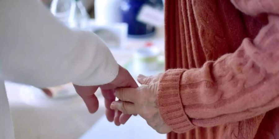 Eine Pflegekraft hält die Hand einer Bewohnerin einer Pflegeeinrichtung. Foto: Britta Pedersen/dpa-Zentralbild/Symbolbild/Archiv