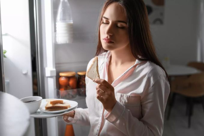 Einige bereiten im Schlaf ganze Menus zu. Frau in Pyjama isst