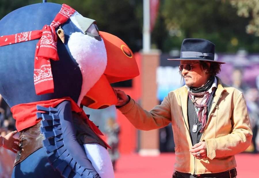 Johnny Depp (58) schüttelt einem Maskottchen die Hand.