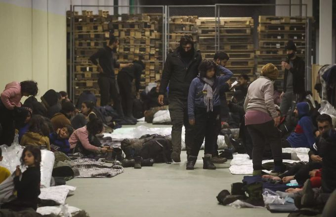 Migranten warten in einer Lagerhalle. belarus