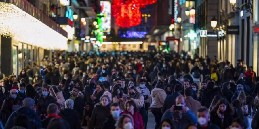 Menschen tragen Schutzmasken gehen durch die Innenstadt in Madrid. Foto: Bernat Armangue/AP/dpa