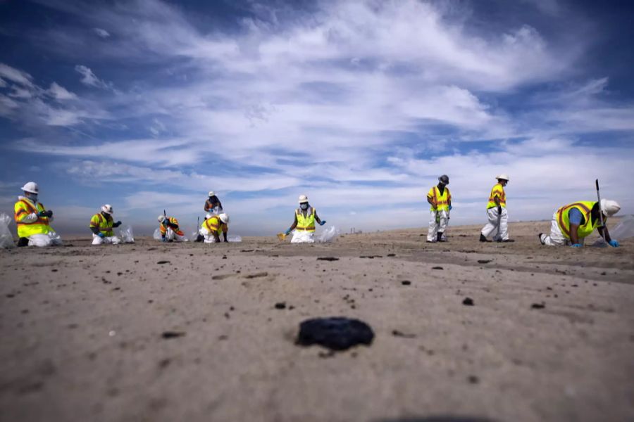 Einsatzkräfte reinigen den Strand bei Huntington Beach.