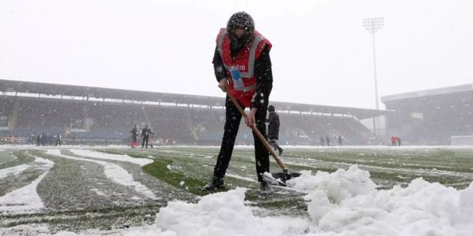 Der Rasen im Staion Turf Moor ist nicht bespielbar: Mitarbeiter räumen den Schnee vom Spielfeld. Foto: Bradley Collyer/PA Wire/dpa Der Rasen im Staion Turf Moor ist nicht bespielbar: Mitarbeiter räumen den Schnee vom Spielfeld. Foto: Bradley Collyer/PA Wire/dpa
