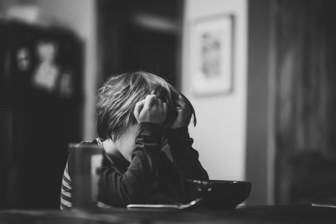 Den Blick für Wanrsignale schärfen – auch Kinder sind den Gefahren der Leistungsgesellschaft ausgesetzt. Kind erschöpft vor Teller - schwarz-weiss.