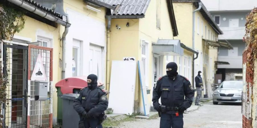 Zwei uniformierte Polizisten stehen in einer Einfahrt an einem Einsatzort der Operation «Luxor» in Graz. Foto: Erwin Scheriau/APA/dpa