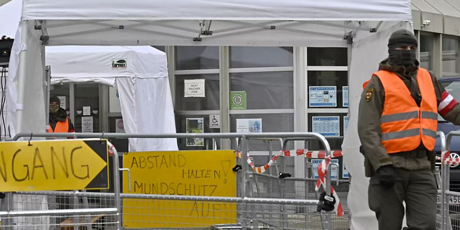 Ein Mann in Warnweste steht vor dem Eingang einer Teststelle in einer Schule in Perchtoldsdorf in Niederösterreich. Foto: Hans Punz/APA/dpa