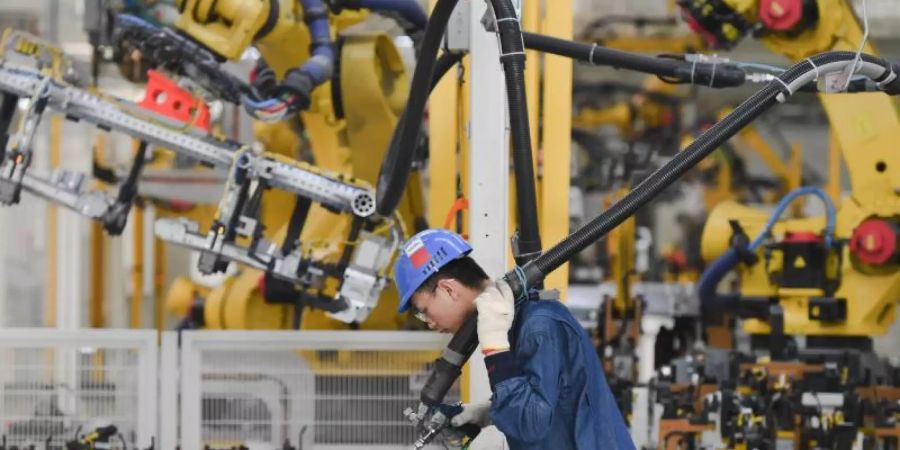 Ein Arbeiter bedient einen Roboter im PKW-Werk der SAIC Motor Corporation Ltd. in der südostchinesischen Provinz Fujian. Foto: Song Weiwei/XinHua/dpa