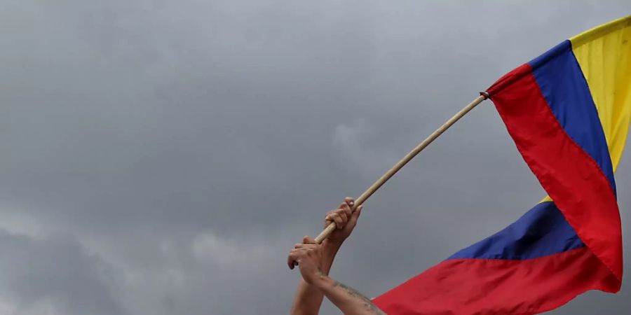 Ein Demonstrant schwenkt während eines «Marsches für das Leben und den Frieden» von Ex-Kämpfern der Farc-Guerilla die Fahne von Kolumbien. Foto: Camila Diaz/colprensa/dpa