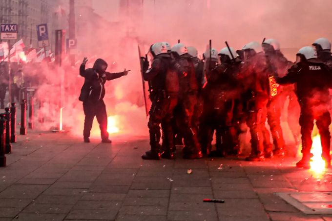 Ein Teilnehmer des Unabhängigkeitsmarschs steht vor einer Gruppe Polizisten. Unabhängigkeitstag in Warschau