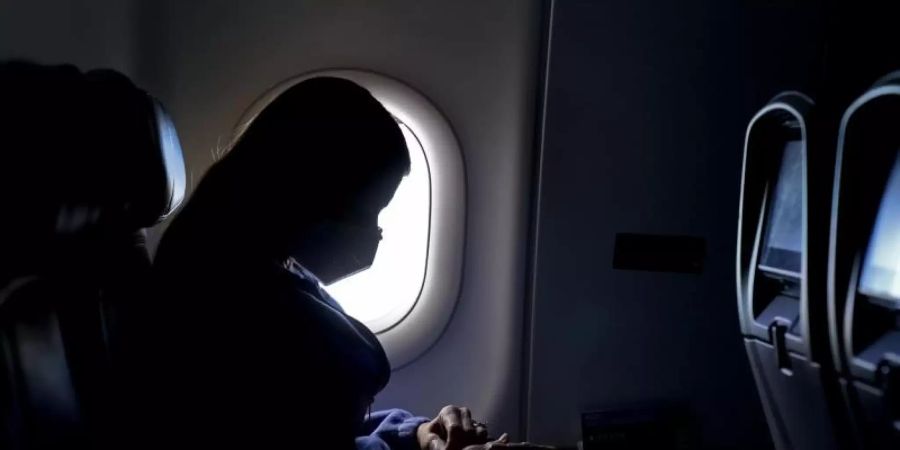 Flug-Passagierin mit Mund-Nasen-Schutz. Foto: Charlie Riedel/AP/dpa