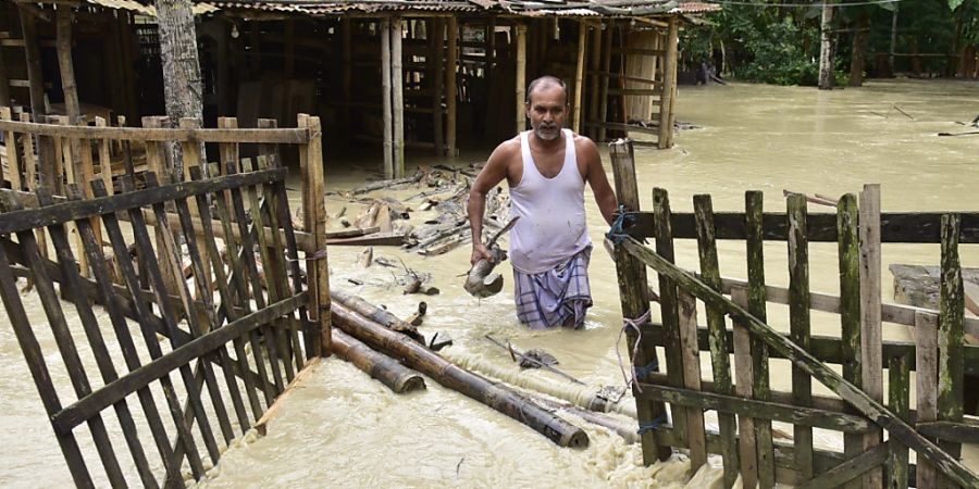 Ein Mann watet im indischen Guwahati durch das Hochwasser auf seinem Grundstück. Foto: Dasarath Deka/ZUMA Press Wire/dpa