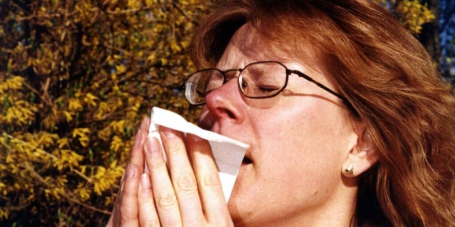 Immer mehr Menschen sind von Allergien betroffen: eine unter Heuschnupfen leidende Frau niest. (Themenbild)
