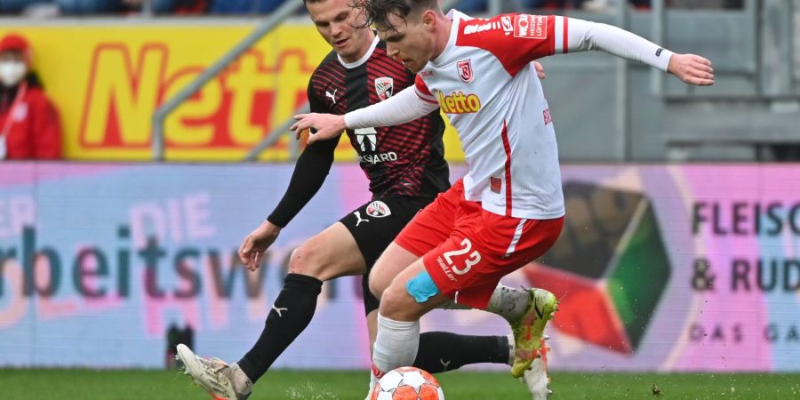 Regensburgs Steve Breitkreuz (r) versucht den Ball im Zweikampf vor Ingolstadts Florian Pick abzuschirmen.