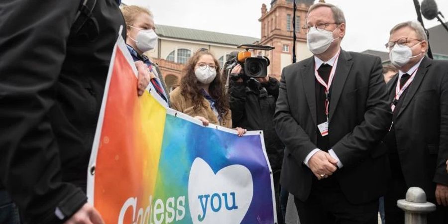 Der Vorsitzende der Deutschen Bischofskonferenz, Georg Bätzing, spricht vor der Synodalversammlung in Frankfurt mit Demonstranten, die eine vielfältigere Kirche fordern. Foto: Sebastian Gollnow/dpa