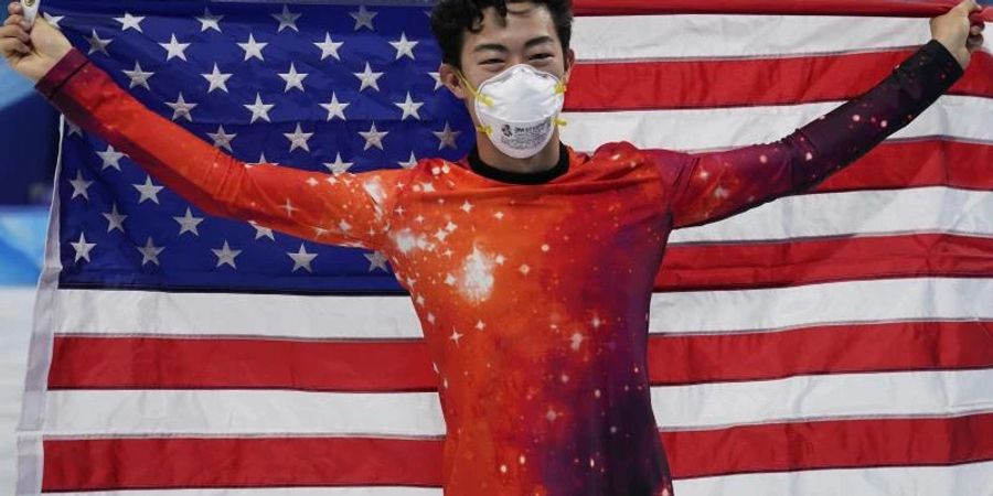 Eiskunstläufer Nathan Chen hält eine amerikanische Flagge hoch und freut sich über seinen Erfolg. Foto: David J. Phillip/AP/dpa