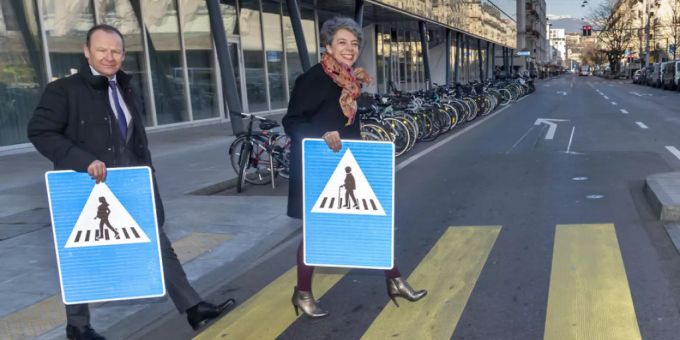 Der Genfer Staatsrat Serge Dal Busco (l.) und die Stadtpräsidentin Sandrine Salerno (r.) präsentieren auf einem Fussgängerstreifen die neuen Verkehrsschilder. genf verkehrsschilder