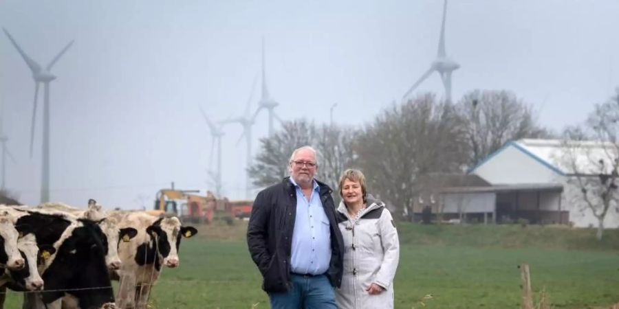 Hermann Oldewurtel und Insa Bock stehen vor den Windkraftanlagen hinter ihrem Wohnhaus in Holtgast. Foto: Sina Schuldt/dpa