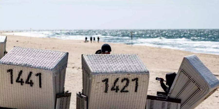 Ein Mann sitzt am Strand von Sylt in einem Strandkorb. Die Urlaubsorte an Nord- und Ostsee in Schleswig-Holstein sind über das Pfingstwochenende gut gebucht. Foto: Axel Heimken/dpa
