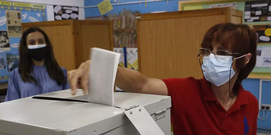 Eine Frau mit Mund-Nasen-Schutz gibt ihre Stimme in einem Wahllokal während der Parlamentswahlen ab. Foto: Petros Karadjias/AP/dpa