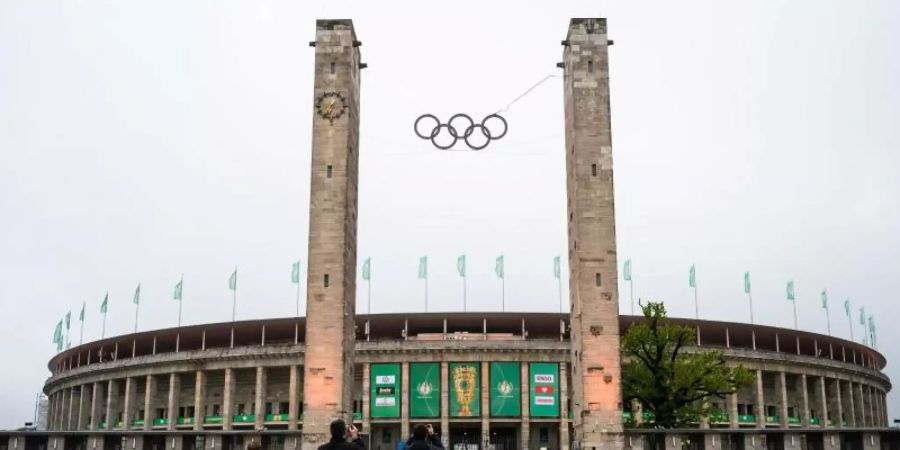 Drei Fussball-Fans stehen vor dem Olympiastadion und machen Fotos. Foto: Christophe Gateau/dpa