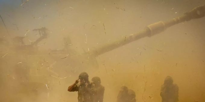 Israelische Soldaten stehen in aufgewirbeltem Staub, nachdem ein Artilleriegeschütz auf Ziele im Gazastreifen gefeuert hat. (Archivbild) Gaza