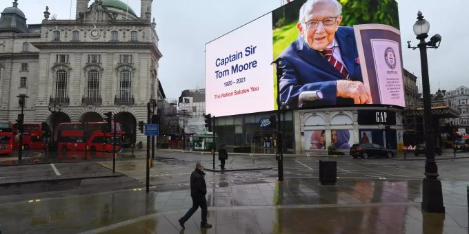03.02.2021, Grossbritannien, London: Ein Bild des verstorbenen Kapitän Sir Tom Moore ist als Tribut am Piccadilly Circus auf einer Anzeigentafel zu sehen. Der nach einer Coronavirus-Infektion gestorbene Rekordspendensammler ist 100 Jahre alt geworden. Foto: Victoria Jones/PA Wire/dpa +++ dpa-Bildfunk +++ Captain Tom nach Corona-Infektion gestorben