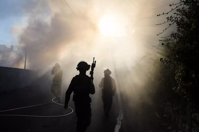 dpatopbilder - 18.05.2021, Israel, Jerusalem: Israelische Sicherheitskräfte sind bei einer Demonstration von Palästinensern im Stadtteil Scheich Dscharrah im Einsatz, während im Hintergrund Rauch aufsteigt. Konflikt in Nahost - Proteste in Jerusalem