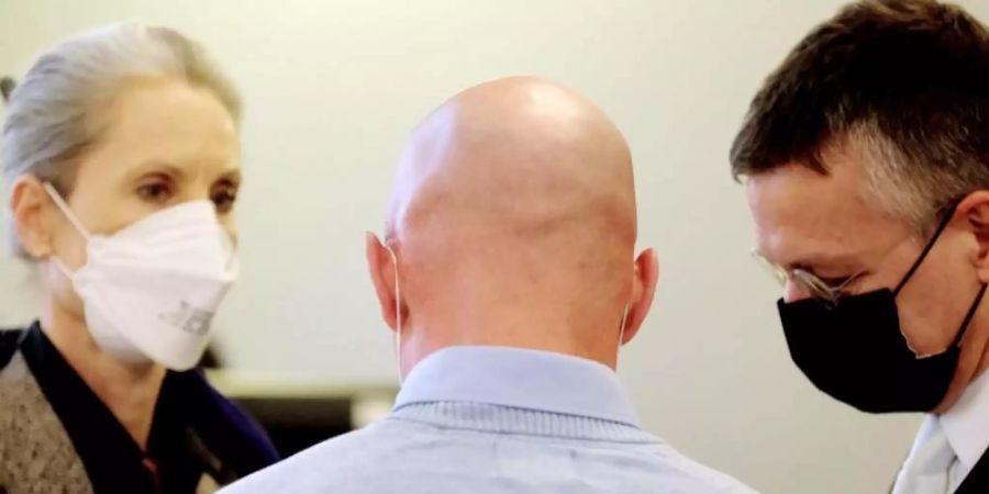 Der Angeklagte (M), ein ehemaliger Bundeswehrsoldat des Kommandos Spezialkräfte (KSK), spricht in einem Saal des Landgerichts mit seinen Anwälten. Foto: Sebastian Willnow/dpa-Zentralbild/dpa