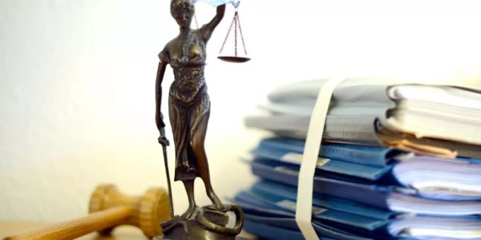 Aktenberg neben Justitia. (Symbolbild) Aktenberg