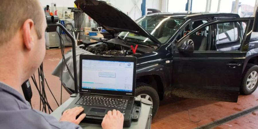 Ein Kfz-Meister lädt ein Software-Update für das Steuergerät der Motorelektronik auf einen Volkswagen Amarok mit Dieselmotor. Foto: Julian Stratenschulte