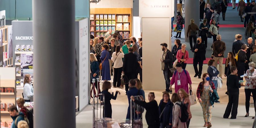 Besucher gehen während des ersten Tags der Frankfurter Buchmesse durch eine Halle. Foto: Sebastian Christoph Gollnow/dpa - Nutzung nur nach schriftlicher Vereinbarung mit der dpa