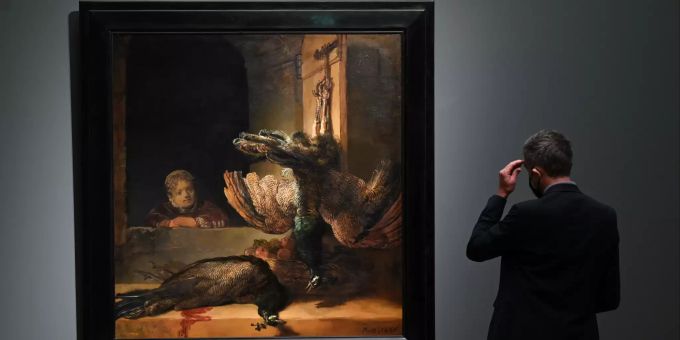 05.10.2021, Hessen, Frankfurt/Main: Ein Mann steht im Ausstellungssaal des Städel Museums vor dem Gemälde «Mädchen mit toten Pfauen (1639)» von Rembrandt. Rembrandt-Ausstellung im Frankfurter Städel Museum