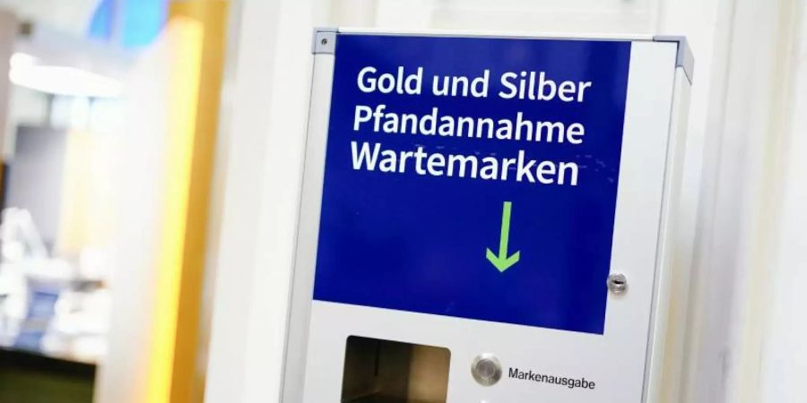 Eine Vorrichtung zur Ausgabe von Wartemarken mit der Aufschrift «Gold und Silber Pfandannahme Wartemarken» hängt im Wartebereich des Leihamts. Foto: Uwe Anspach/dpa
