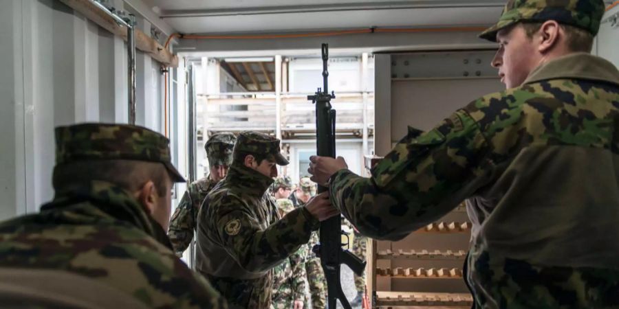 Soldat der Schweizer Armee händigt eine Waffe aus.