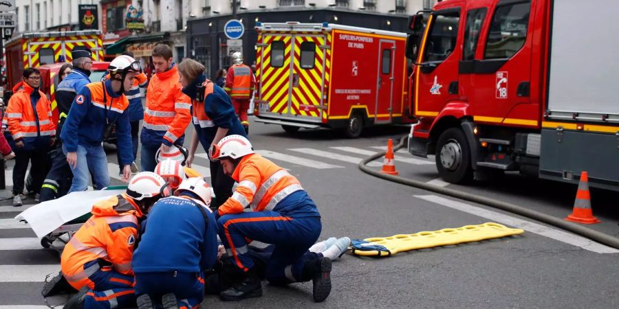 Feuerwehrleute versorgen nach einer Explosion in einer Bäckerei in der Rue de Trevise einen Verletzten.