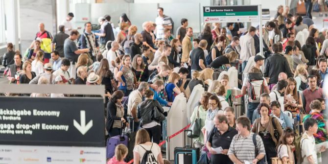 Passagiere stehen im Flughafen Zürich Schlange.