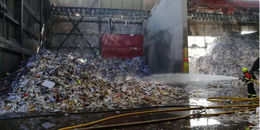 Ein Feuerwehrmann löscht den Brand innerhalb der Papierfabrik in Utzenstorf BE.