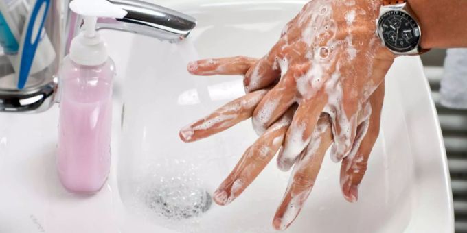 Ein Mann wäscht seine Hand in einem Badezimmer. waschen