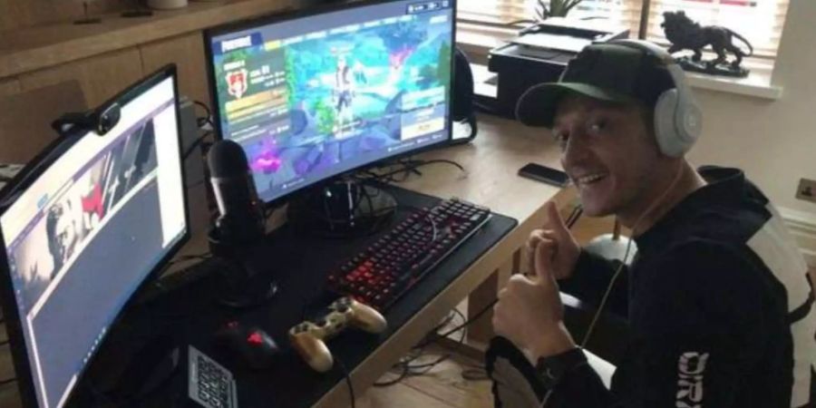 Mesut Özil sitzt vor seiner Battlestation und zeigt die Daumen hoch.