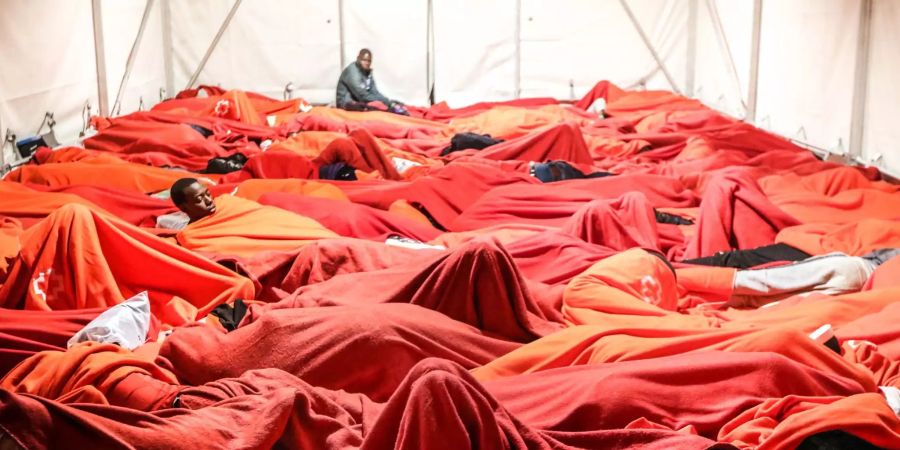 Hunderte Flüchtlinge übernachten auf dem Boden eines Zeltes im Hafen von Malaga (ESP).