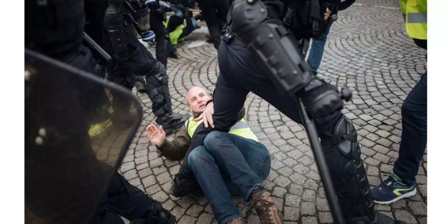 Ein Demonstrant wird von Polizisten zu Boden geworfen.