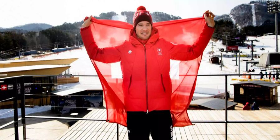 Dario Cologna posiert in Pyeongchang mit Schweizer Flagge.