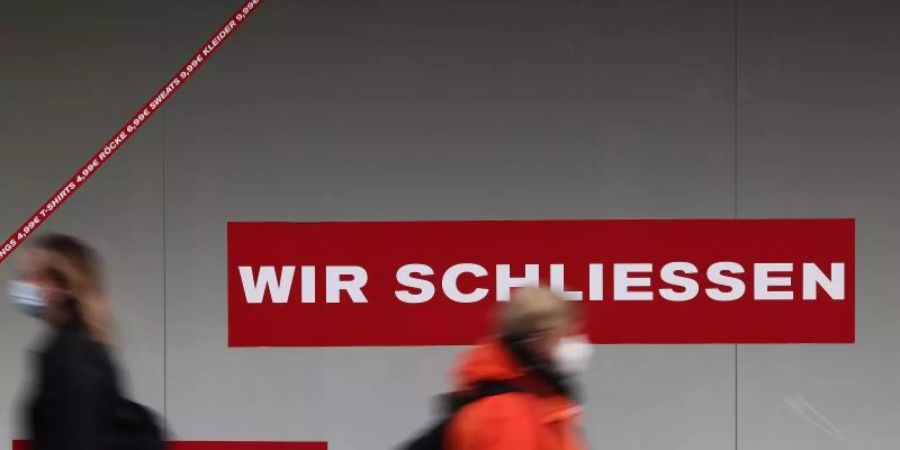 Passanten gehen in der Kölner Innenstadt an einem geschlossen Ladenlokal vorbei. Foto: Oliver Berg/dpa
